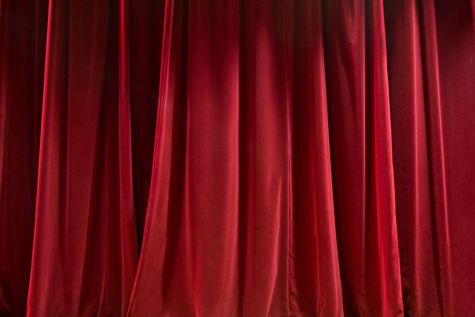 Blinded curtains of red color and made of silk fabric hanging under bright light
