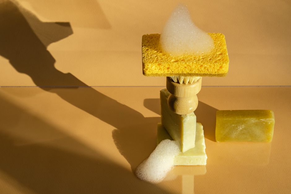 Artistic arrangement of eco-friendly bath essentials with a foamy sponge set against a warm backdrop.